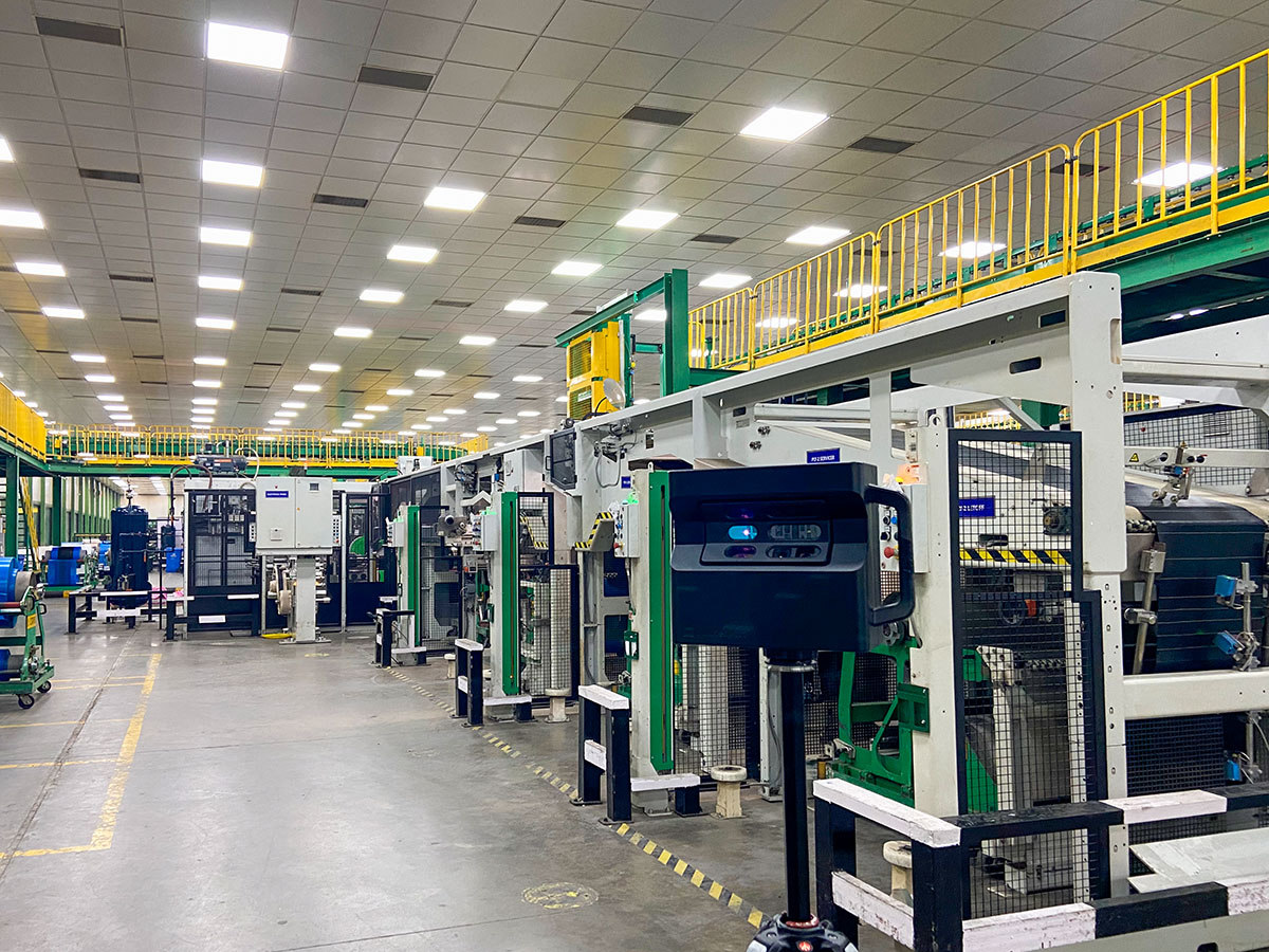 A line of advanced green and white Tyre Building Machines (TBM) on the factory floor.