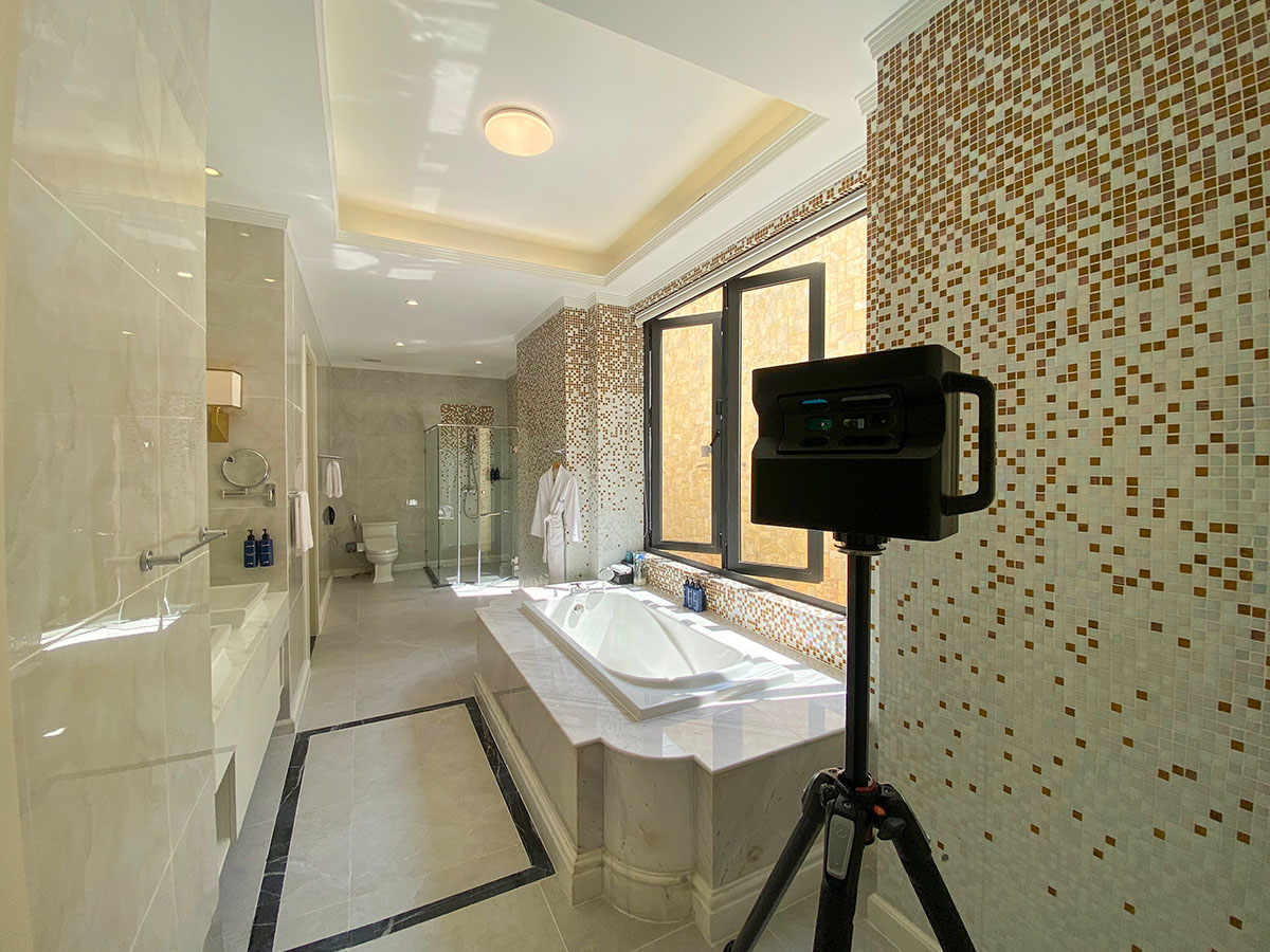 A 3D spatial scanner positioned next to a luxurious marble bathtub and mosaic tile wall inside a Radisson Blu resort bathroom.