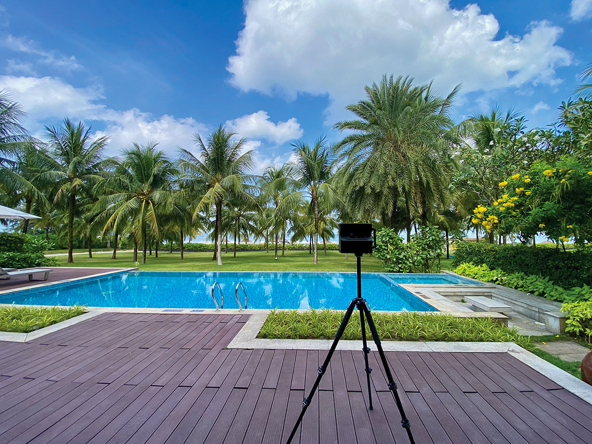 A view from a villa at Radisson Blu Resort Phu Quoc showing the pool and beach in the background, with a Matterport Pro2 camera on a tripod in the foreground.