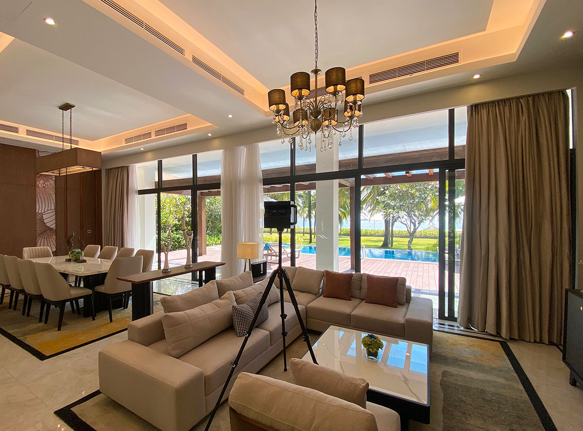 A Matterport Pro2 camera capturing the spacious living and dining area of a Radisson Blu villa, featuring floor-to-ceiling windows overlooking the ocean.