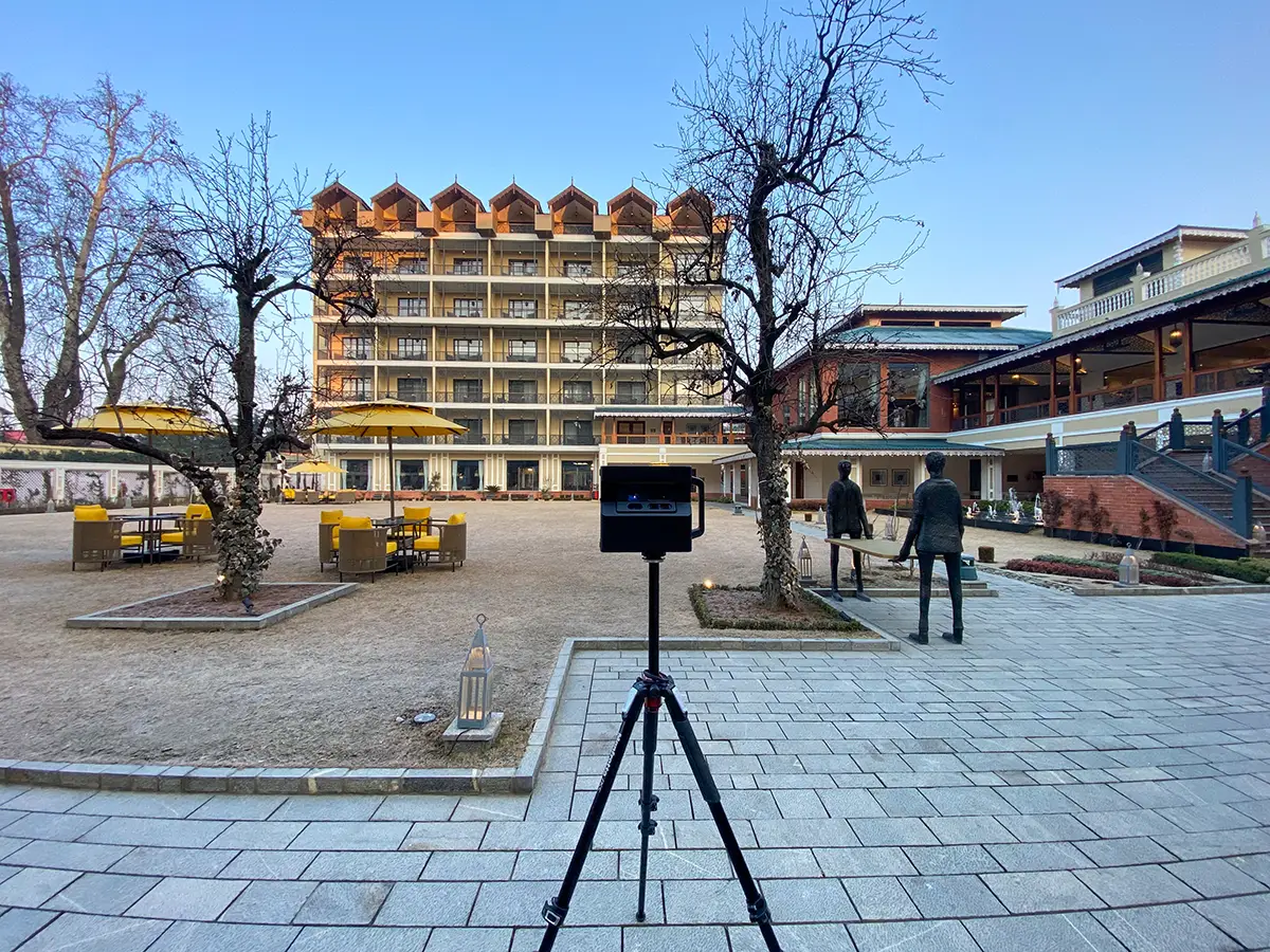 A tablet displaying a Matterport tour of an Indian luxury hotel, with charts showing growth metrics in the background.